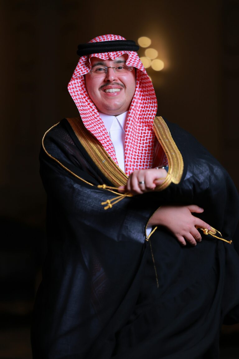 A smiling man in traditional Saudi clothing, embodying cultural elegance and celebration.